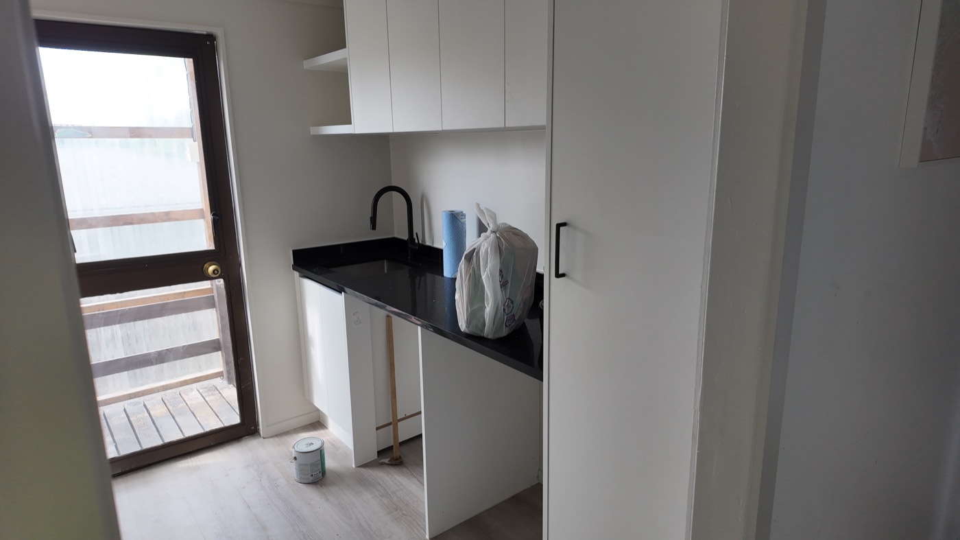 Completed utility area with new cabinetry and black benchtop