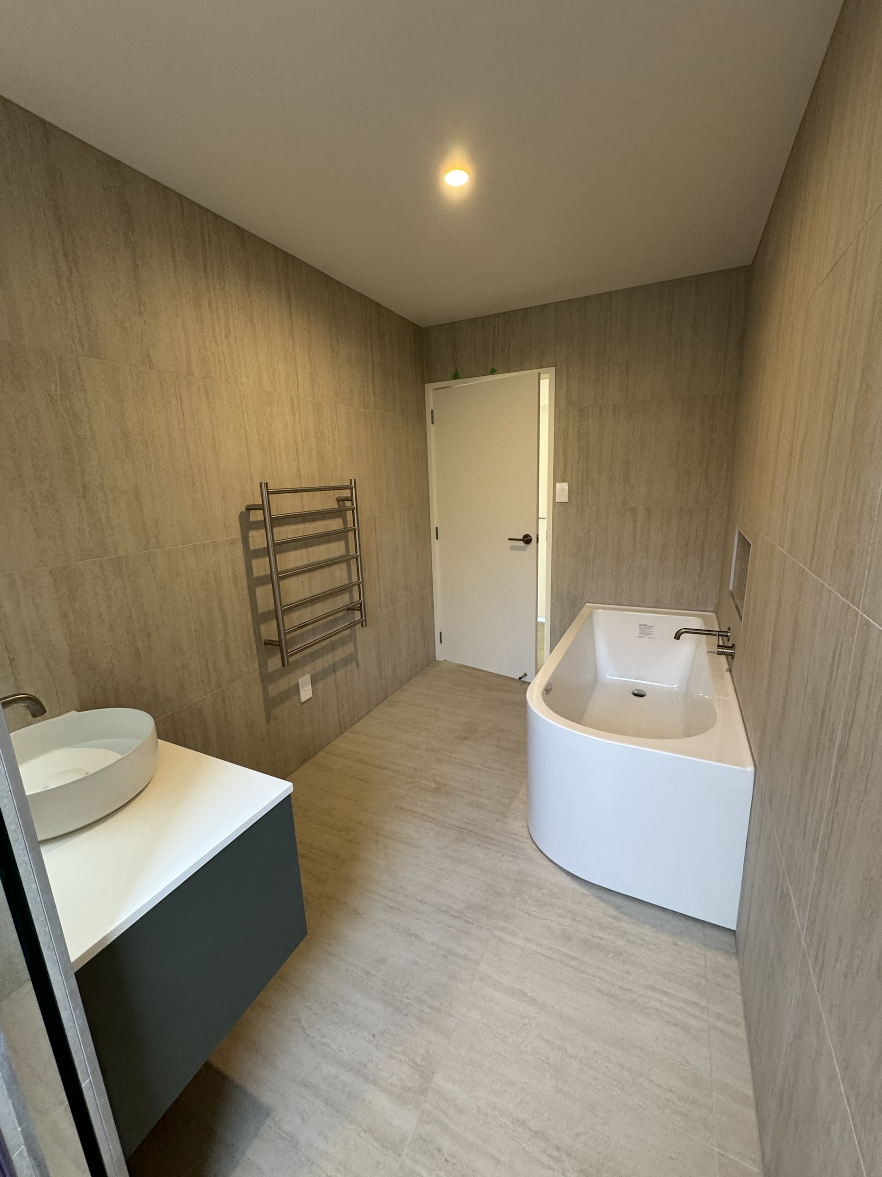 Family bathroom with freestanding bath and full-height cream tiles