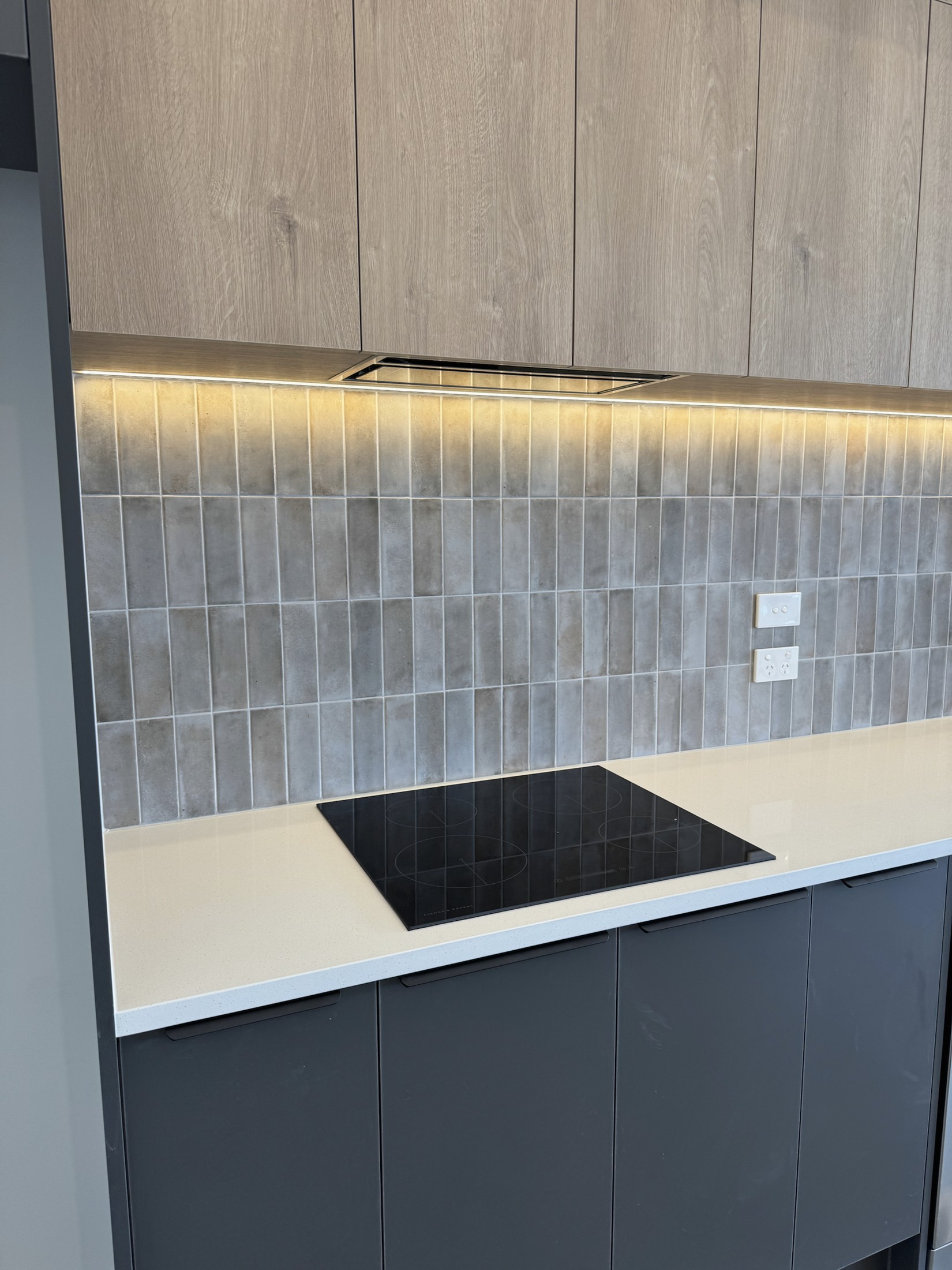 Anthracite kitchen cabinetry with illuminated tiled splashback