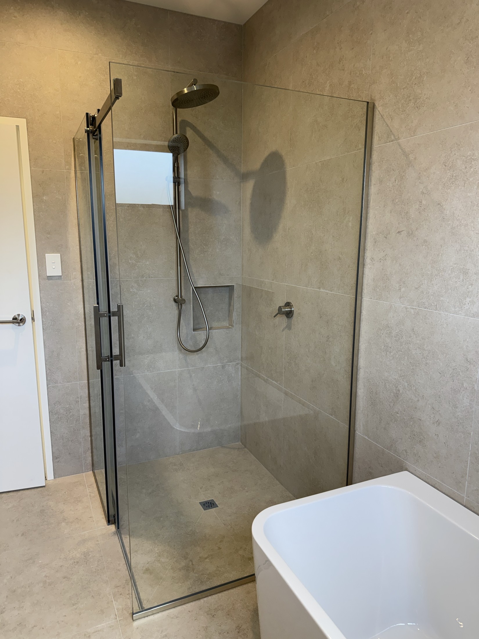 Frameless glass shower with brushed-nickel fittings and tiled niche