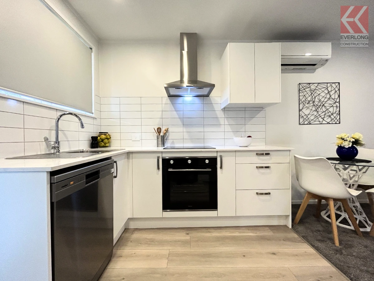 Bright kitchen with white cabinets, tiled splashback and small dining corner